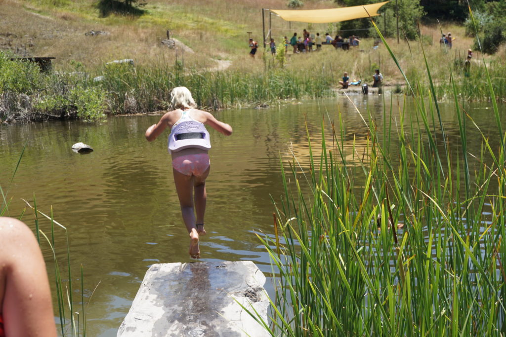 girl jumping in pond at camp bohemia